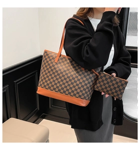 Close-up of checkerboard print tote bag with brown leather handles and matching pouch