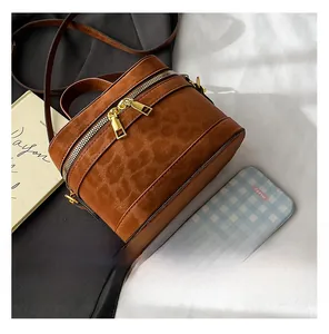 Detailansicht der runden braunen Zylindertasche mit Leopardenmuster und Goldreißverschluss