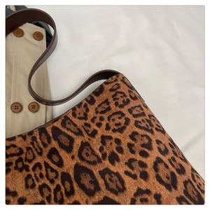 Detail shot of leopard print tote bag with brown leather strap against a trench coat