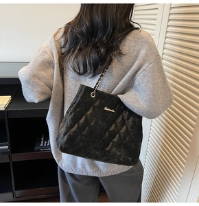 Close-up of black quilted leather tote bag with elegant chain strap and metal logo