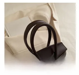 Detail of dark brown leather handbag featuring unique window-style contrast pattern
