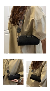 Close-up of black cylinder crossbody bag with ethnic embroidered strap and gold hardware