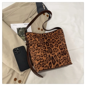 Detail shot of leopard print tote bag with brown leather strap next to a magazine
