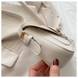Détails d'un sac bandoulière en similicuir crème avec coutures fines et boucles dorées