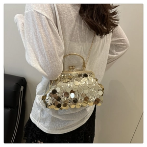 Detail of golden sequin shell bag with metal clasp and chain strap on a model