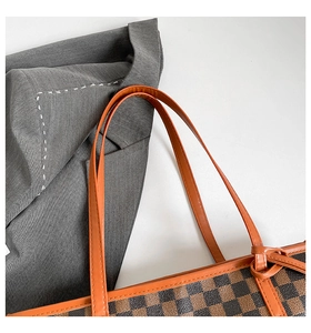 Close-up of dual-tone checkerboard tote bag with bright orange knotted strap detail