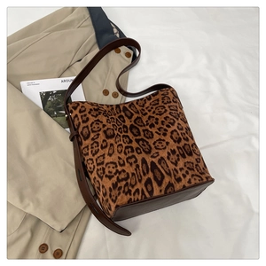 Detail of leopard print bucket bag with brown leather base and adjustable shoulder strap