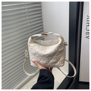 Detailed view of white quilted heart pattern and metallic buckle on handbag strap