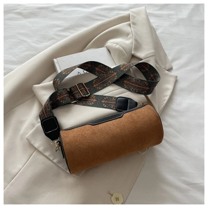 Macro detail of brown suede cylinder bag with wide ethnic geometric embroidered strap