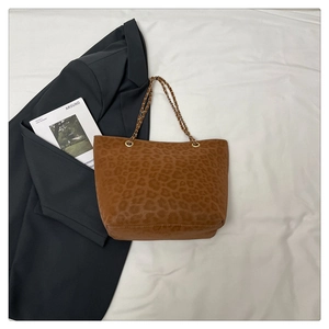 Détail du sac cabas léopard avec bandoulière chaîne dorée sur fond blanc minimaliste