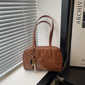 Brown faux leather tote bag with wooden bead charm in a natural light scene