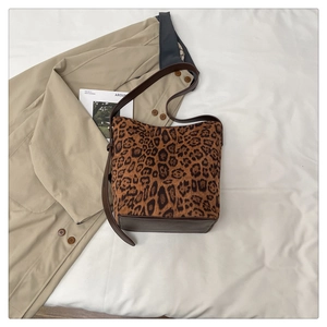 Detail of leopard print bucket bag with brown leather base and adjustable strap