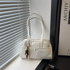 Minimalist white tote bag with wooden beads and front pocket displayed by window light