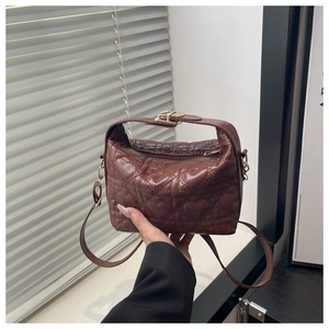 Macro detail of the heart-pattern quilted stitching and gold hardware on brown handbag