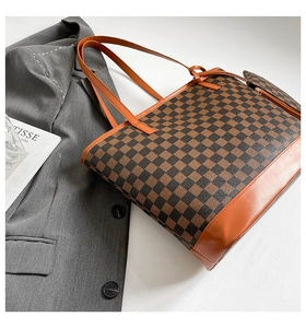 Close-up of checkerboard tote bag with orange leather handles and matching pouch