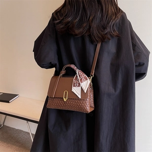 Brown woven crossbody handbag with silk scarf and gold lock shown on model back