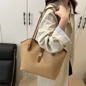 Brown litchi grain leather tote bag with gold metal buckle shown on a model