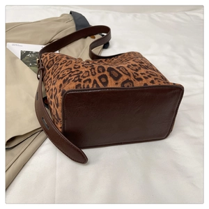 Detail of leopard print tote bag with brown leather bottom and wide adjustable strap