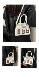 Detailed view of white mini house bag featuring unique red window patterns and silver lock