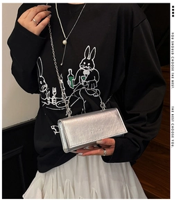 Silver metallic mini bag with mim logo, chain strap, and top handle shown on a model
