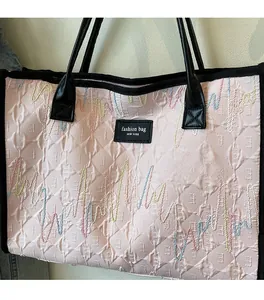 Close-up of pink quilted tote bag featuring colorful wavy embroidery and fashion label