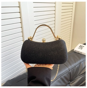 Close-up of black glitter evening clutch with gold handle and sparkling rhinestone lock