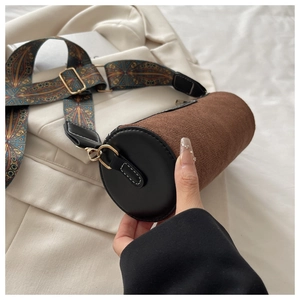Close-up of brown suede cylinder bag with vintage woven strap and golden metal hooks