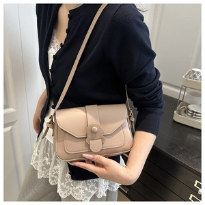 Detail of a milk tea colored crossbody bag featuring a front slot and flap closure