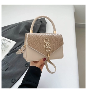 Detail of fashion crossbody bag with woven texture flap and gold tassel metal buckle