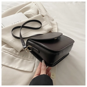 Detail of dark brown leather crossbody bag with a gold metal twist lock and matte finish