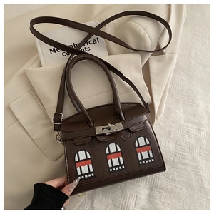 Detail of dark brown crocodile embossed handbag with unique arched window design and lock