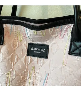 Detail of pink embossed tote bag with colorful wave embroidery and leather fashion tag