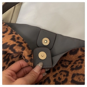 Detail of leopard print tote bag with golden magnetic snap closure and grey lining