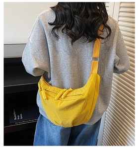 Crossbody moon bag in bright yellow nylon featuring three woven zipper pulls on a wide strap