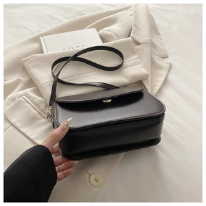 Detail of dark brown leather crossbody bag with golden twist lock and layered design