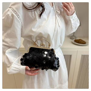 Close-up of black sequined evening clutch with gold metal clasp and chain strap on model