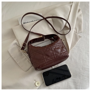 Detail of dark brown heart-quilted handbag with gold hardware and shoulder strap