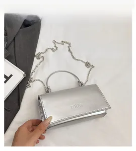 Detail view of silver metallic bag with chain strap and embossed logo on the flap