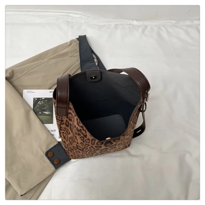 Close-up of leopard print tote bag interior featuring metal magnetic buckle and brown handles