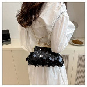 Detail of black sequin evening bag with gold metal handle and chain on white dress