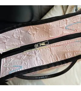 Detail of pink quilted tote bag showing smooth metal zipper and colorful embroidery