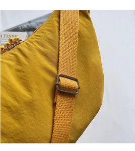 Detail of adjustable wide shoulder strap and smooth zipper on bright yellow nylon bag