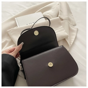 Detail of dark brown leather handbag showing magnetic closure and fine matte texture