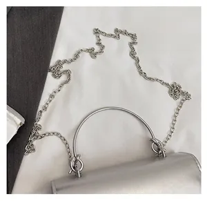 Detail of silver chain bag with a metallic ring handle and sleek crossbody metal strap