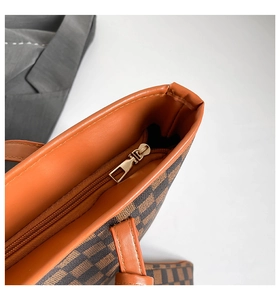 Close-up of golden zipper closure and brown checkered pattern on tote bag detail