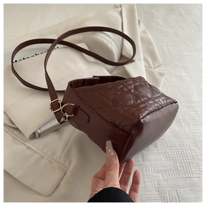Close-up of dark brown quilted handbag with heart embroidery and gold metal details
