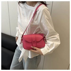 Close-up of pink square crossbody bag with textured faux leather and buckle detail
