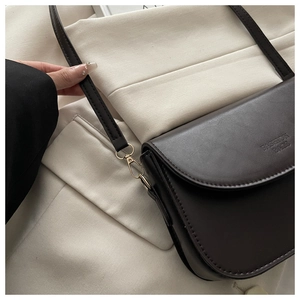 Detail of dark brown saddle bag with golden metal buckle and Fashion Bags logo embossed