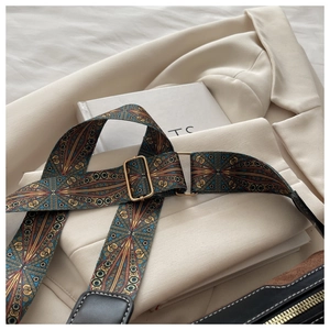 Detail of adjustable geometric woven shoulder strap with gold buckle and leather ends
