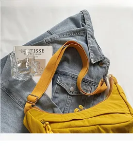 Detail of a bright yellow half-moon nylon crossbody bag with an adjustable wide shoulder strap